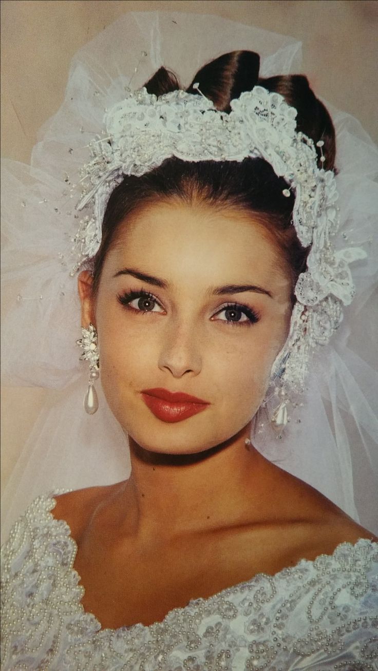 an old photo of a woman wearing a wedding dress and veil with pearls on her head