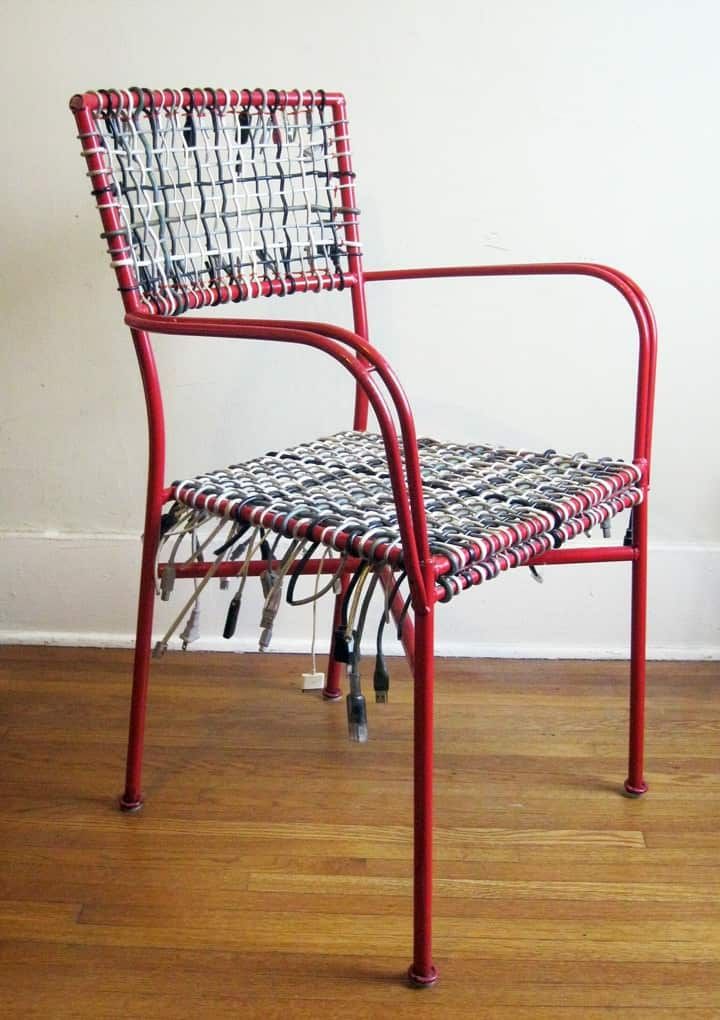 a red chair sitting on top of a hard wood floor next to a white wall