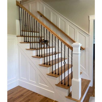 a white staircase with wooden handrails and black railing on the bottom floor in a home