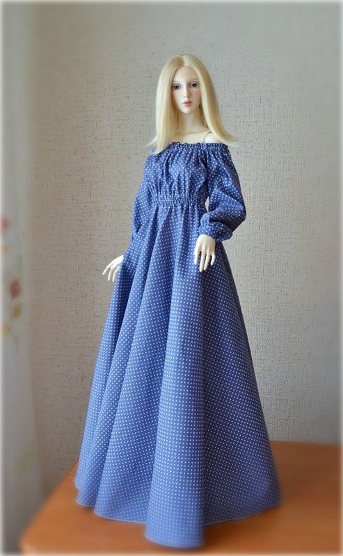 a doll is wearing a blue dress on a table