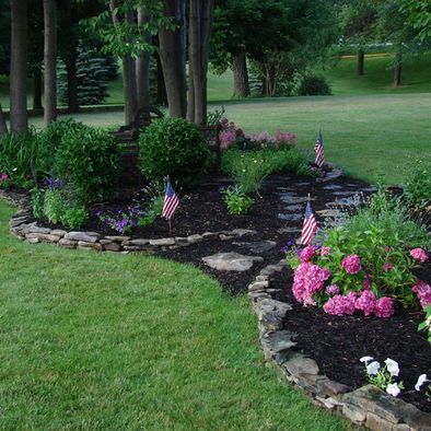 a garden with flowers and flags in the middle of it, surrounded by trees on both sides