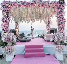 an outdoor wedding setup with pink and white flowers on the aisle, purple carpeted steps leading up to it