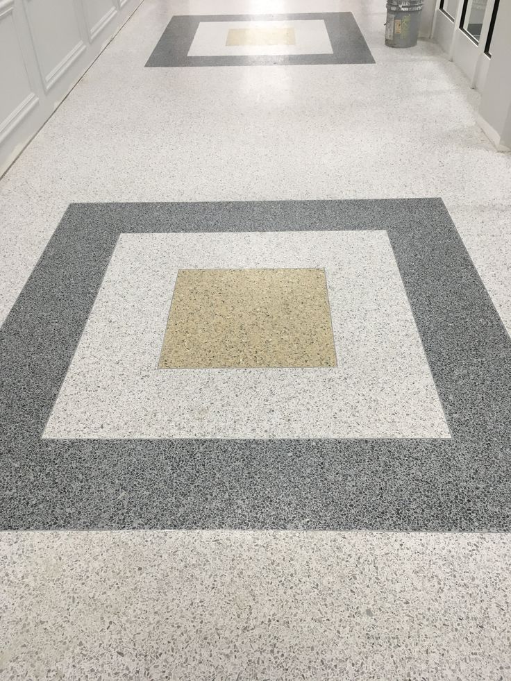 an empty hallway with white walls and grey flooring is seen in this image from the bottom