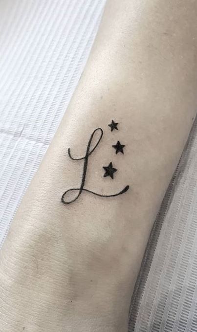 a small tattoo with the letter l on it's left arm and stars in the middle