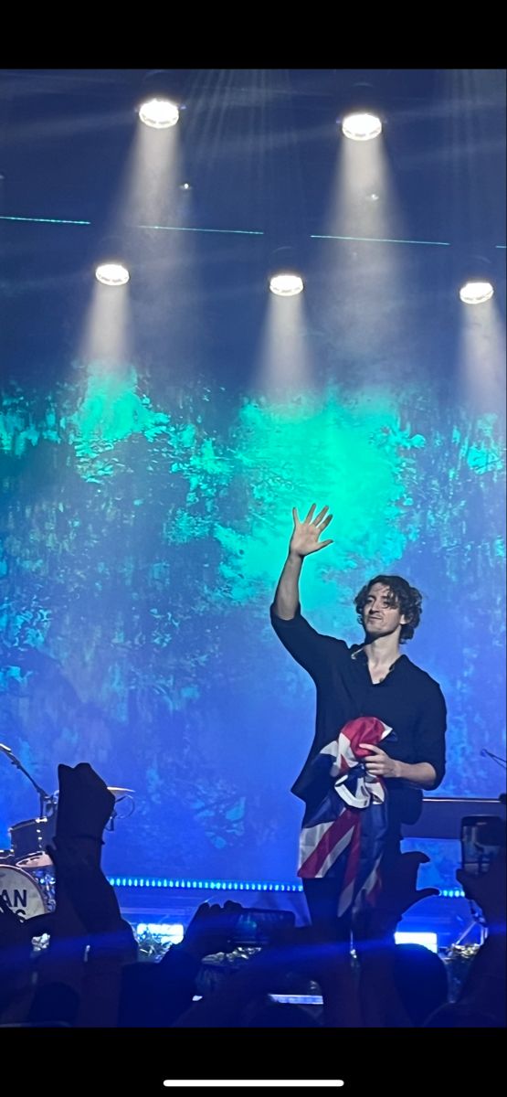 a man standing on top of a stage with his arms in the air