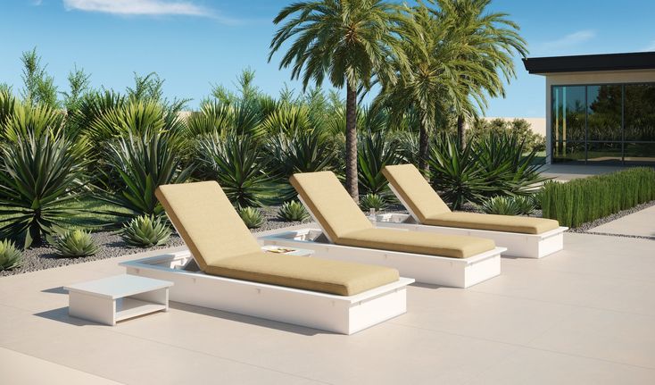 three white lounge chairs sitting on top of a cement floor next to trees and bushes