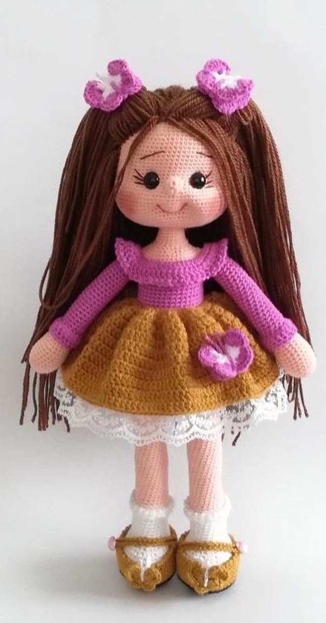 a crocheted doll with brown hair wearing a yellow dress