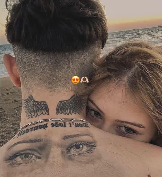 a man and woman with tattoos on their backs are looking at the camera while they're close to each other