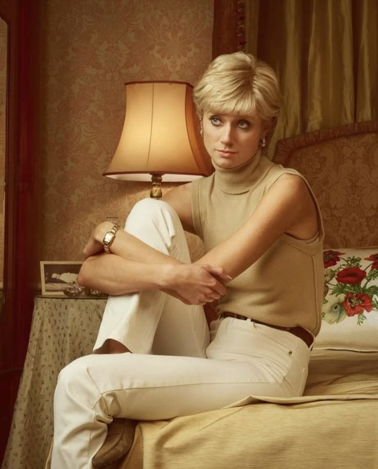 a woman sitting on top of a bed next to a lamp