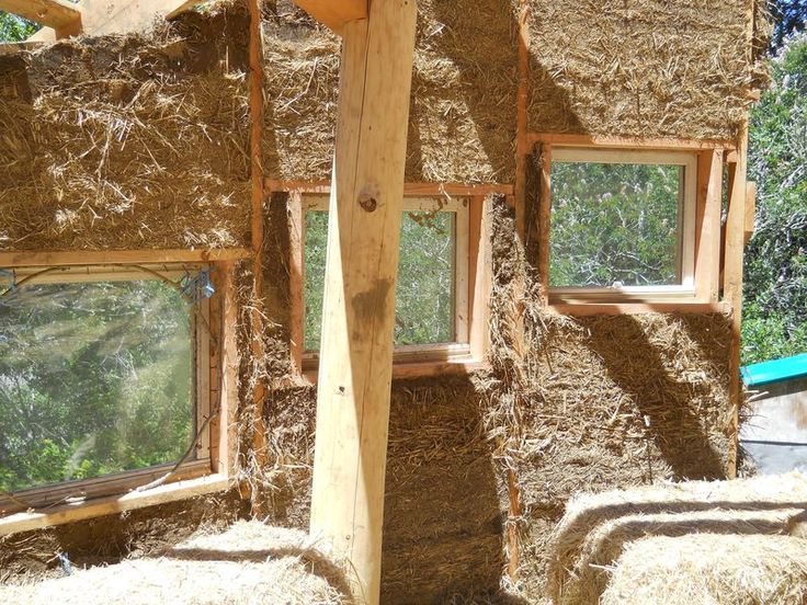 straw bales are stacked on top of each other in front of windows and walls