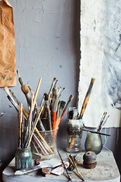 an assortment of paintbrushes and other art supplies sit on a table in front of a painting easel