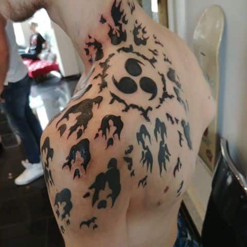 the back of a man's shoulder with black and white tattoos on his body