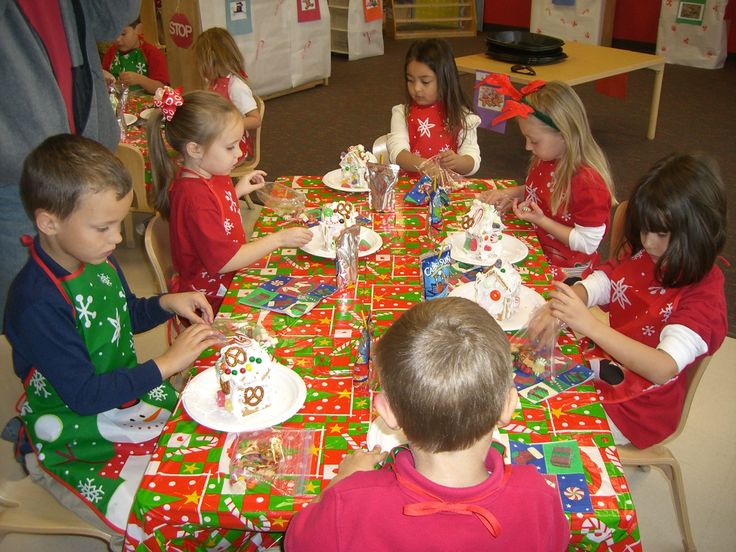 a group of children sitting at a table with christmas decorations on it and plates in front of them