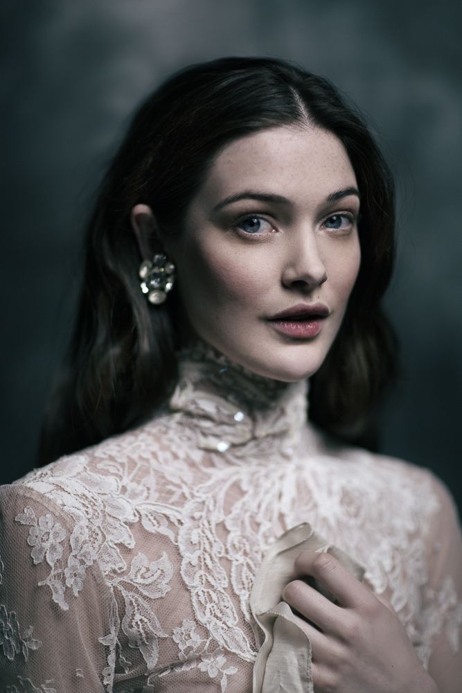 a woman in a white dress is posing for a photo with her hands on her chest