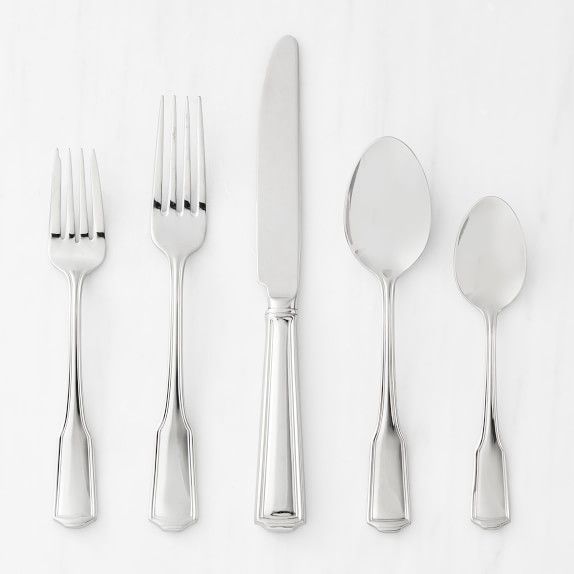 a set of five silver flatware with spoons, knives and forks on a white surface