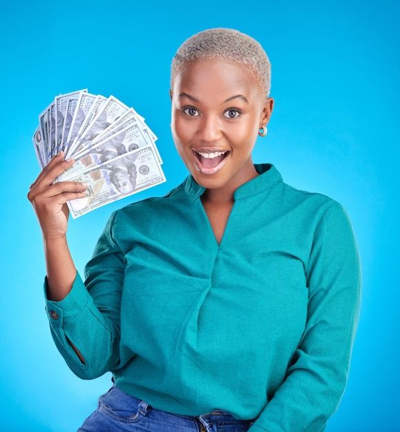 a woman holding money in one hand and smiling at the camera while standing against a blue background