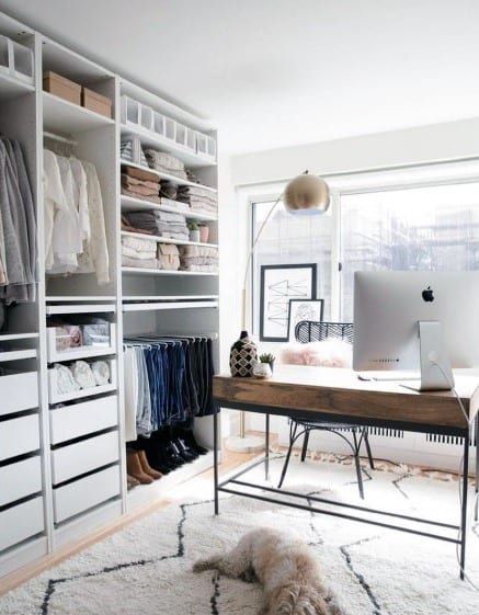 a computer on a desk in front of a closet full of clothes and shoes,