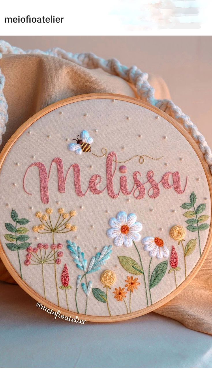 a hand embroidered name with flowers and a bee on it