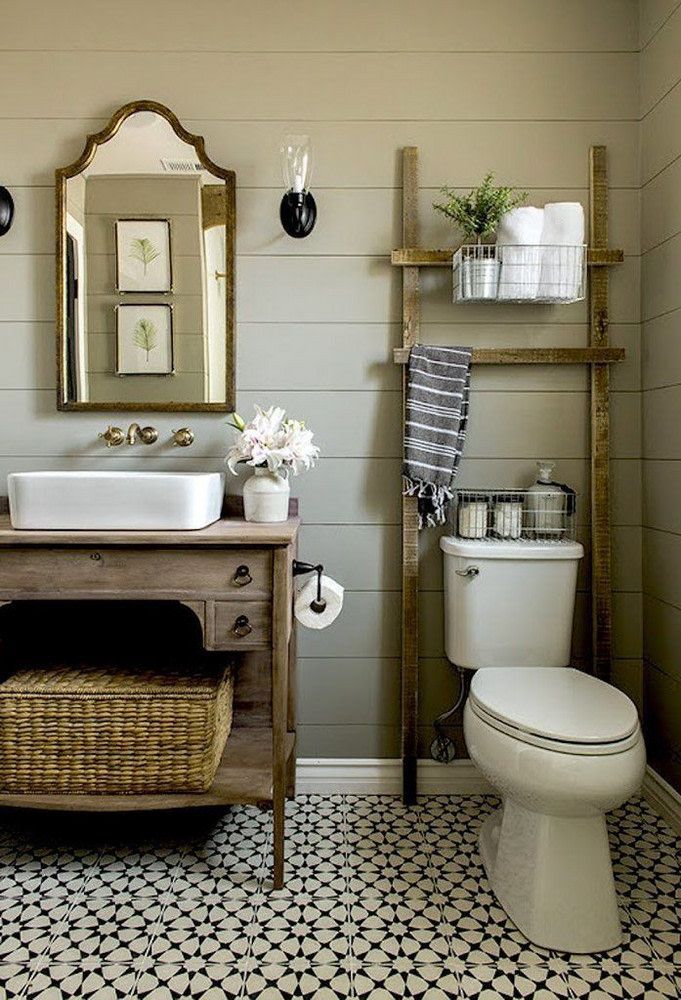 a white toilet sitting next to a bathroom sink under a mirror on top of a wooden shelf