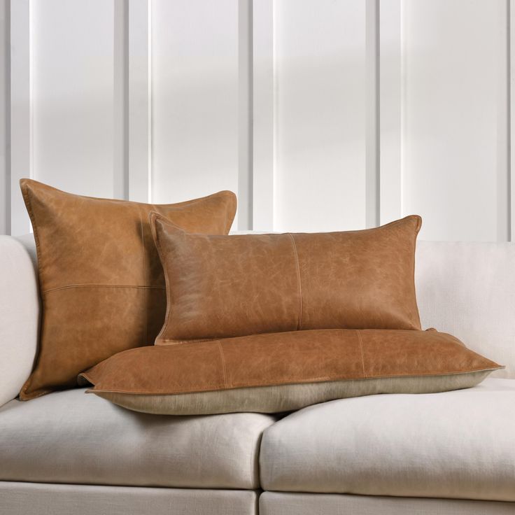 two brown pillows sitting on top of a white couch