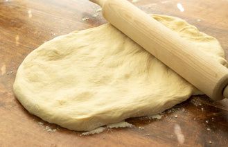 a rolling dough on top of a wooden table