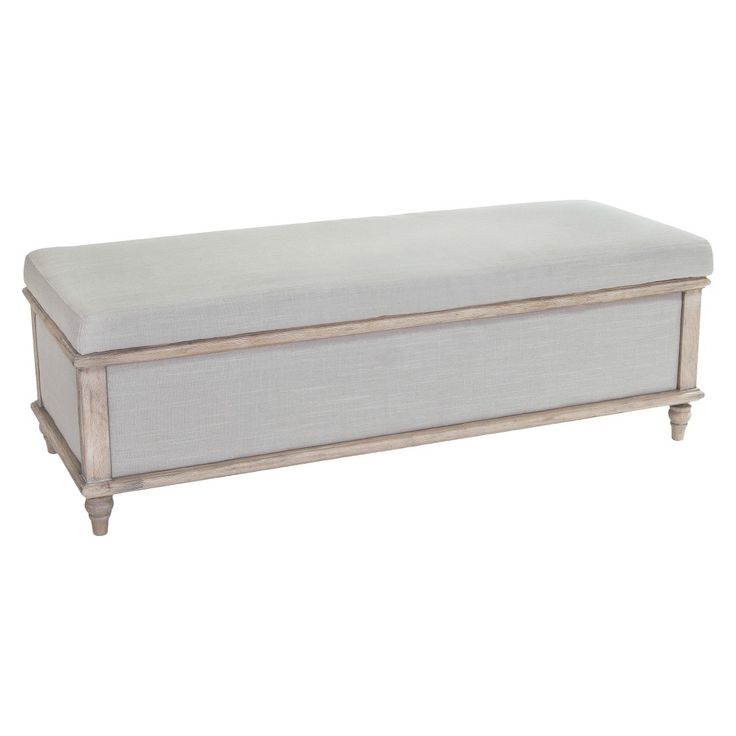 an upholstered bench with white linen and wood trimmings, against a white background