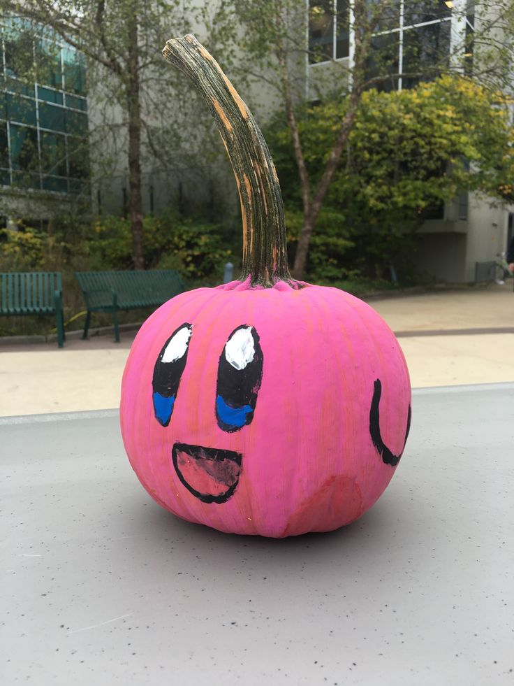 a pink pumpkin with an evil face painted on it's side sitting in front of a building