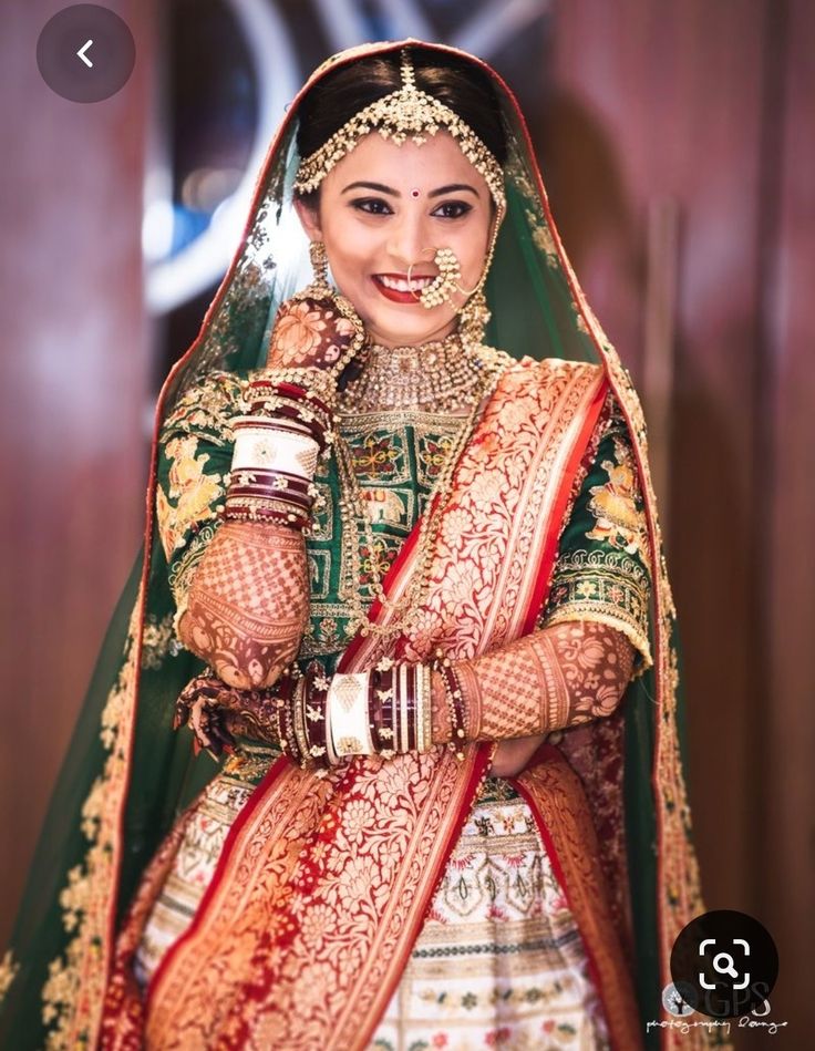 a woman in a green and red bridal outfit with her hands on her hip