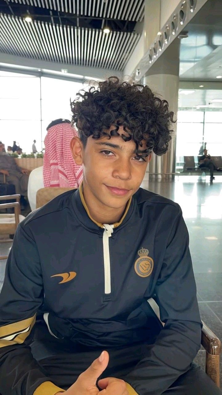 a young man with curly hair sitting down