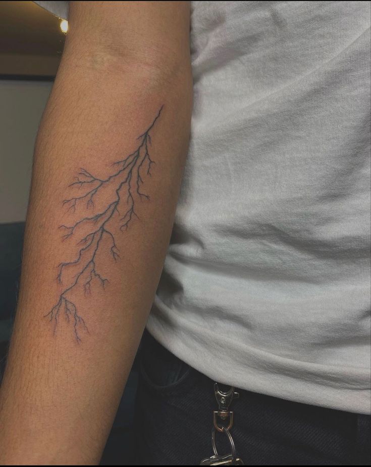 a man with a tattoo on his arm that has some branches growing out of it