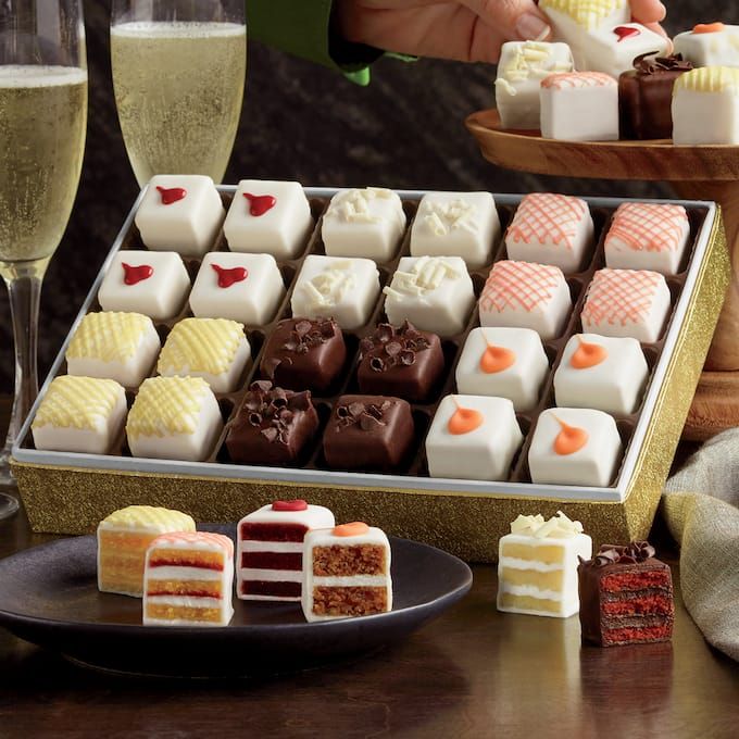 a tray filled with assorted desserts next to wine glasses