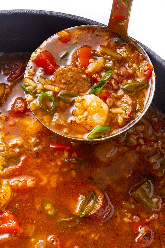 a ladle full of soup with shrimp and vegetables