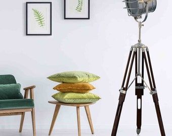 a green chair sitting next to a lamp on top of a wooden tripod stand