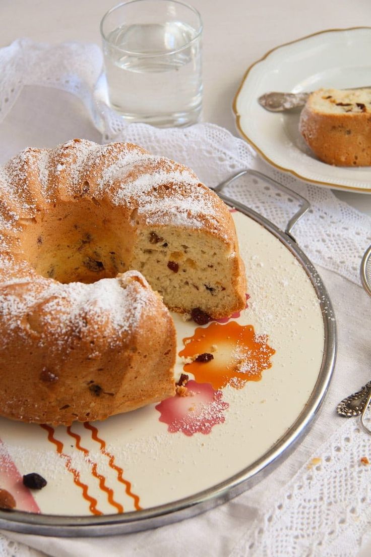 a bundt cake on a plate next to a glass of water