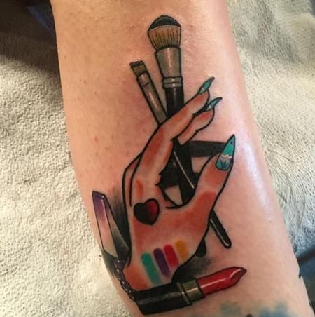 a woman's foot with a tattoo on it that has makeup brushes and lipstick