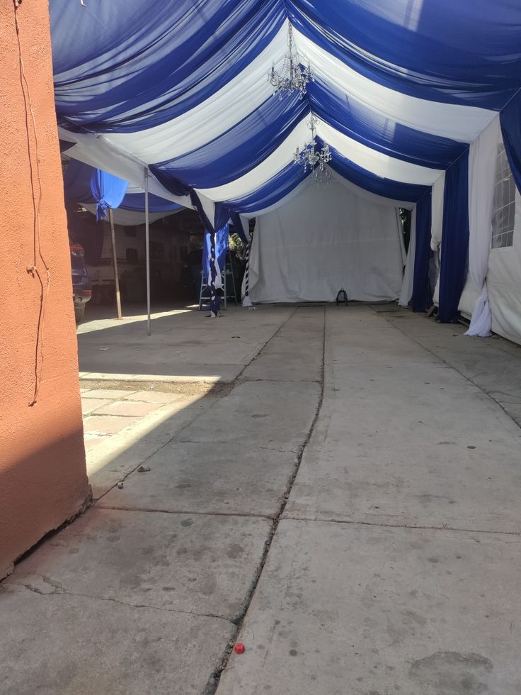 a large blue and white tent sitting on top of a cement floor next to a building