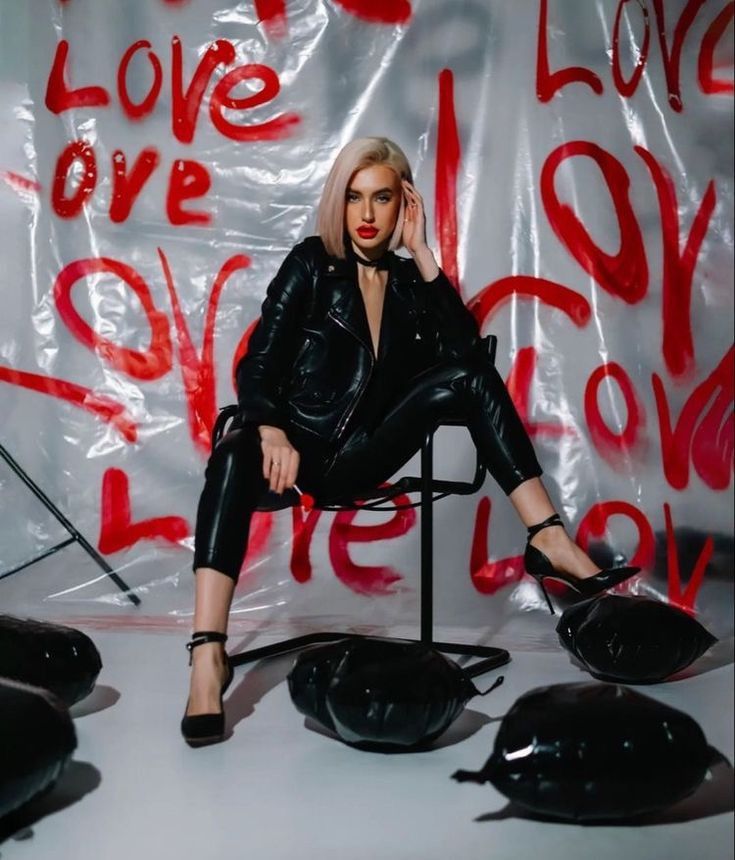 a woman sitting on top of a chair in front of a wall covered with graffiti