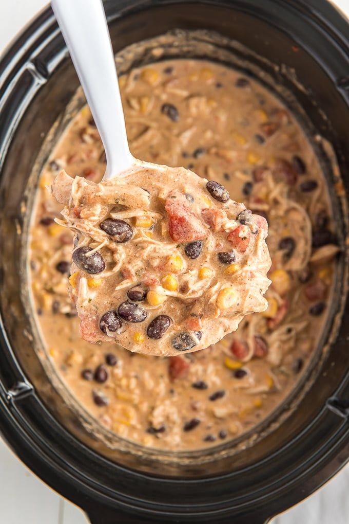 a spoon full of beans and corn in a slow cooker