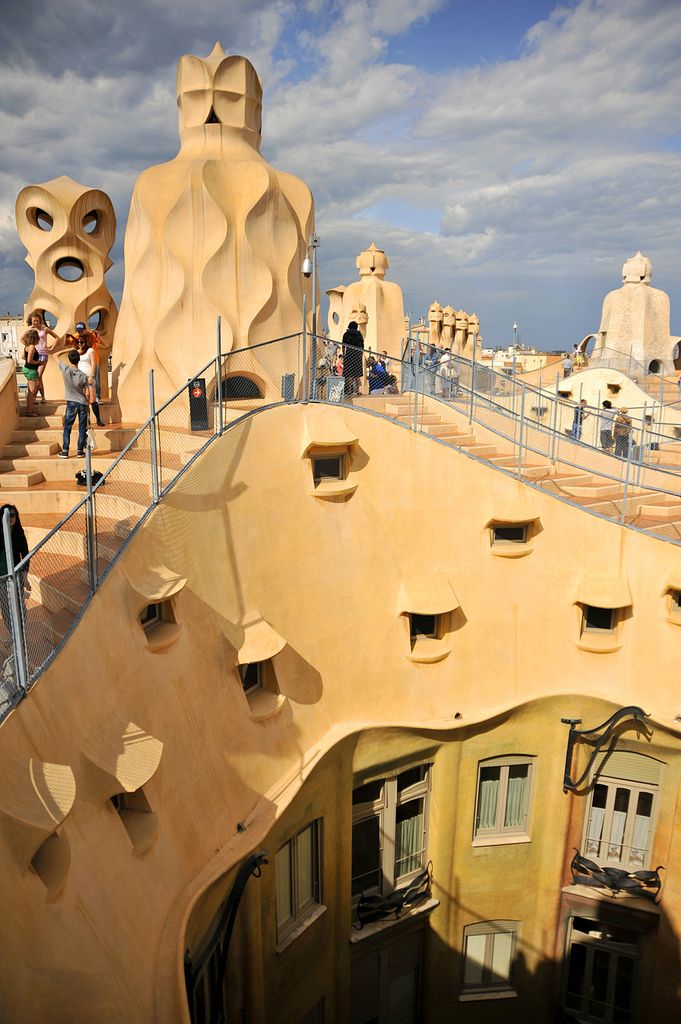 people are standing on the roof of a building with unusual shaped windows and architecture in the background