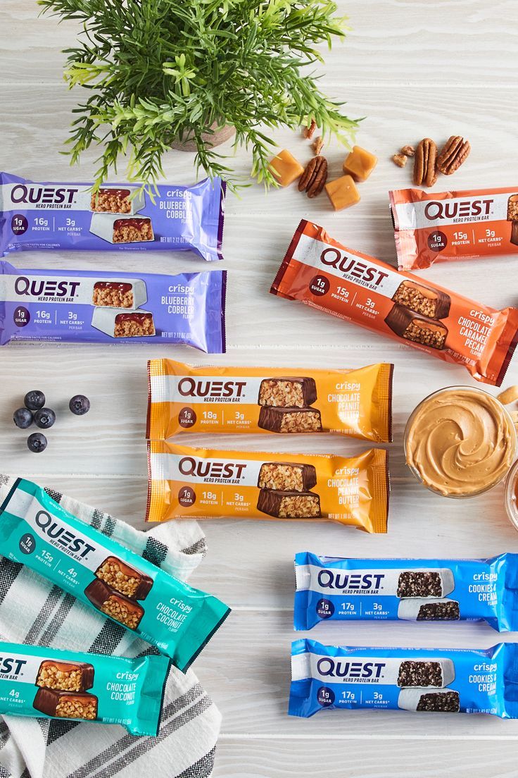 an assortment of quest bars on a table with nuts and blueberries next to them