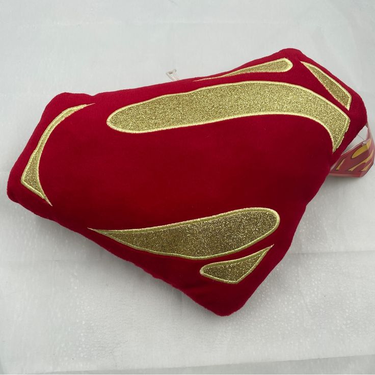 a red pillow with gold foil on the front and back of it, sitting on a white surface