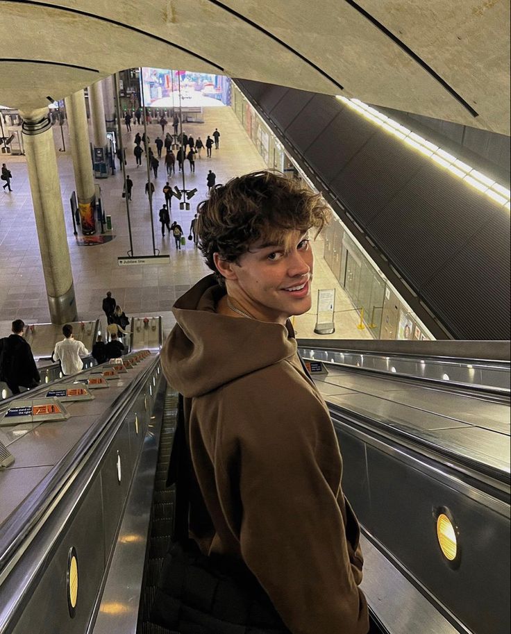 a young man is standing on an escalator