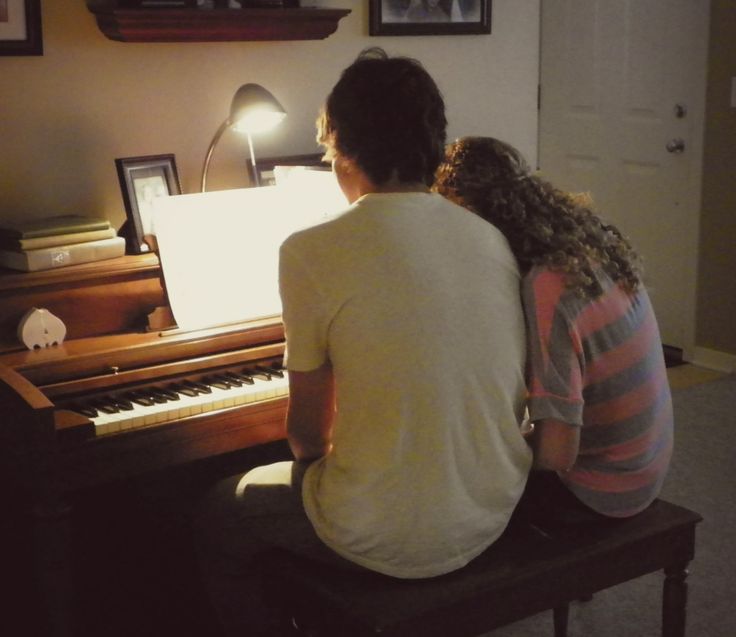 two people sitting at a piano in front of a light