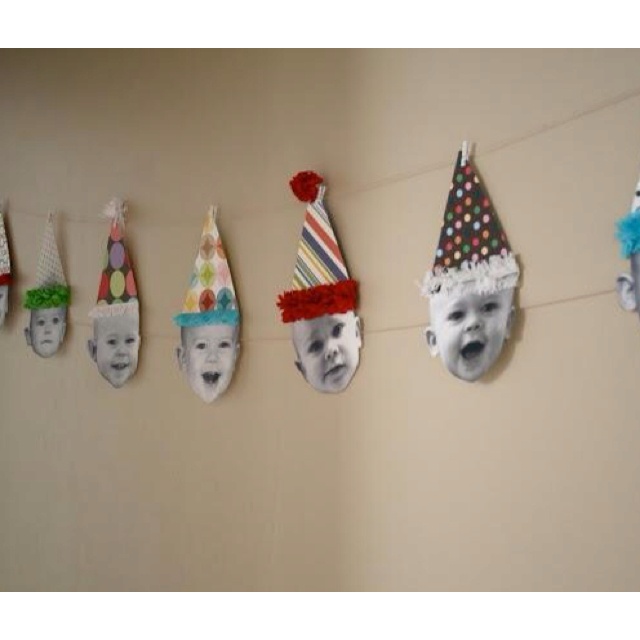 there are many masks hanging on the wall with faces painted on them and one is wearing a party hat