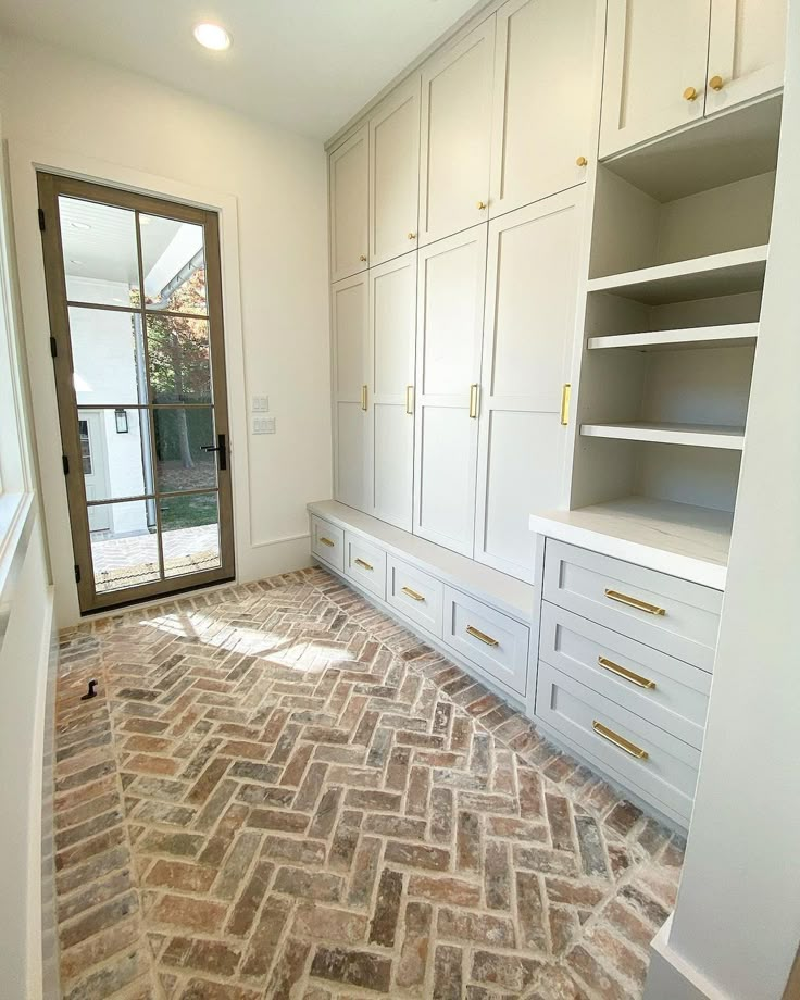 an empty room with white cabinets and brick flooring