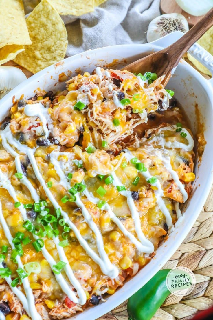 mexican chicken enchilada casserole in a white dish with tortilla chips