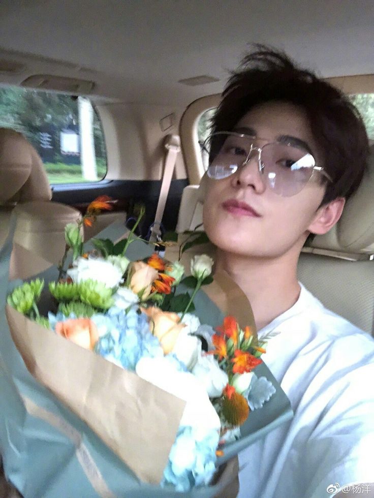 a man sitting in the back seat of a car holding a paper bag filled with flowers