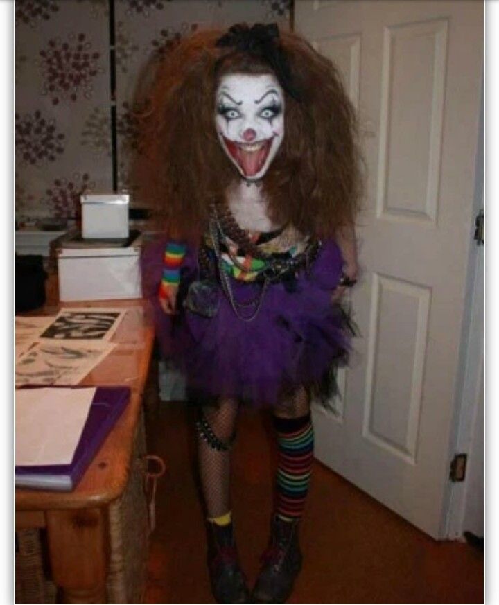 a woman dressed as a clown standing next to a table