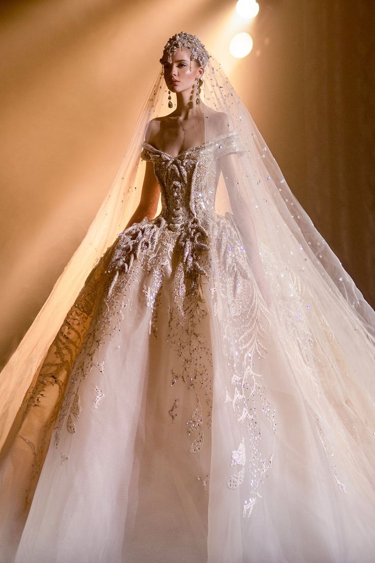 a woman in a wedding dress with a long veil on her head and hands behind her back