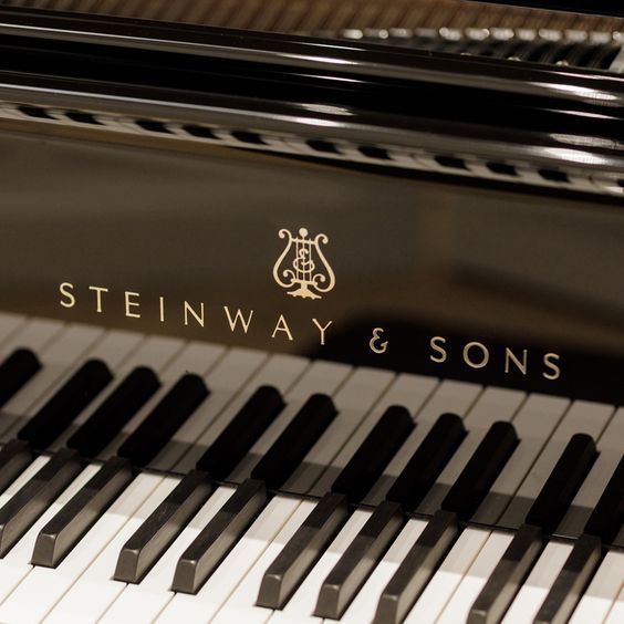 the steinway & sons logo is engraved on the piano's black, polished keys